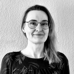 Eine Frau mit Brille und langem Haar blickt in die Kamera