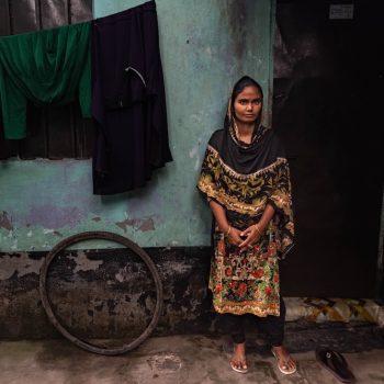 Eine bangladeschische Frau steht vor einer Wand.