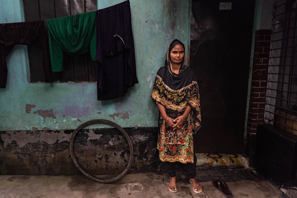 Eine bangladeschische Frau steht vor einer Wand.