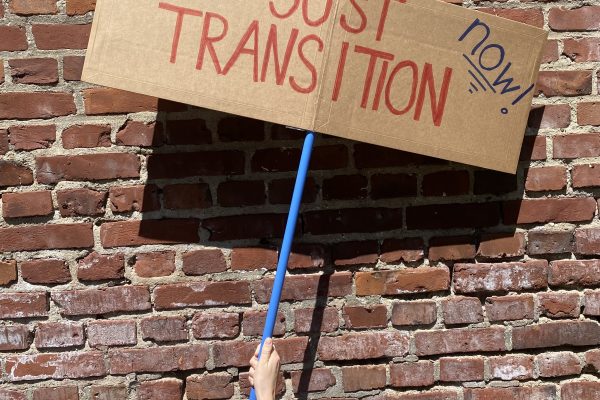 EIn Plakat mit Aufschrift "Just Transition" vor eine Backsteinwand.