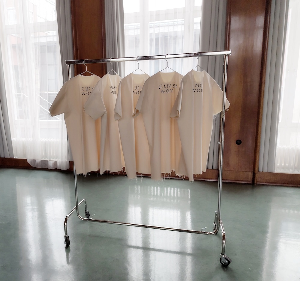 Auf einem Kleiderständer hängen fünf weiße T-Shirts.