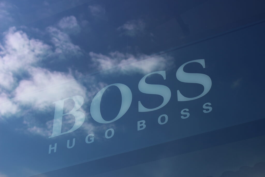 Logo der Marke Hugo Boss an einer Gebäudewand, an der sich Wolken spiegeln