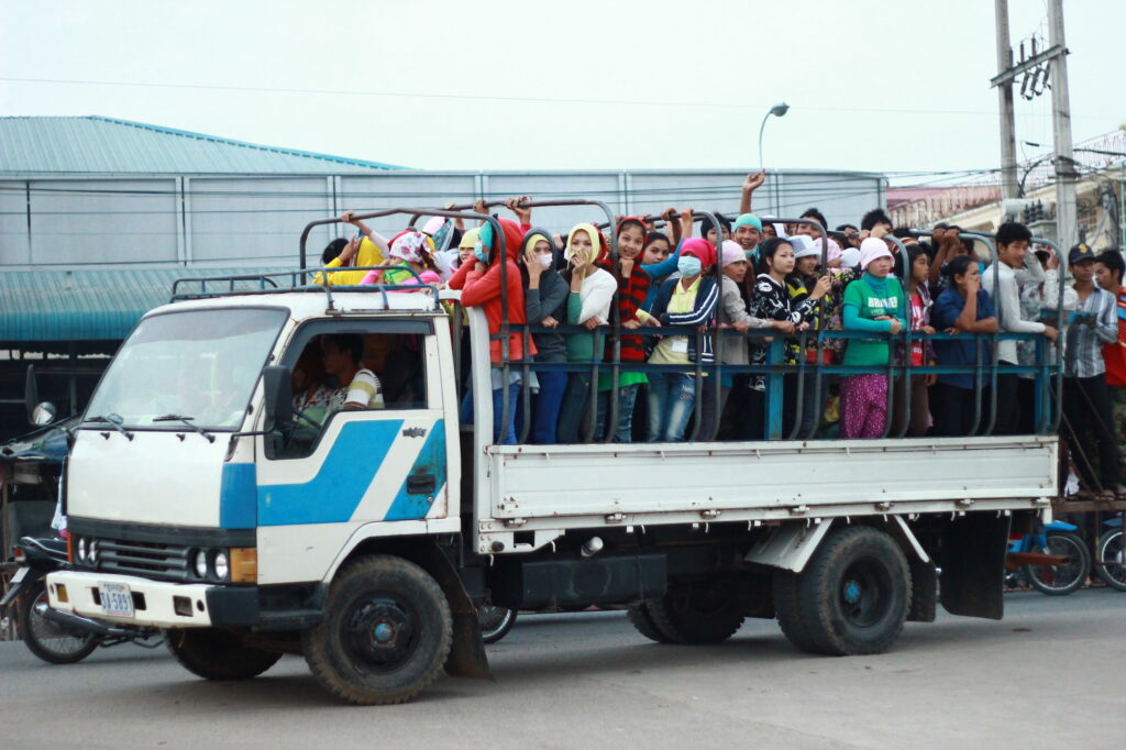 Ein weißer Pritschenwagen voller Menschen.